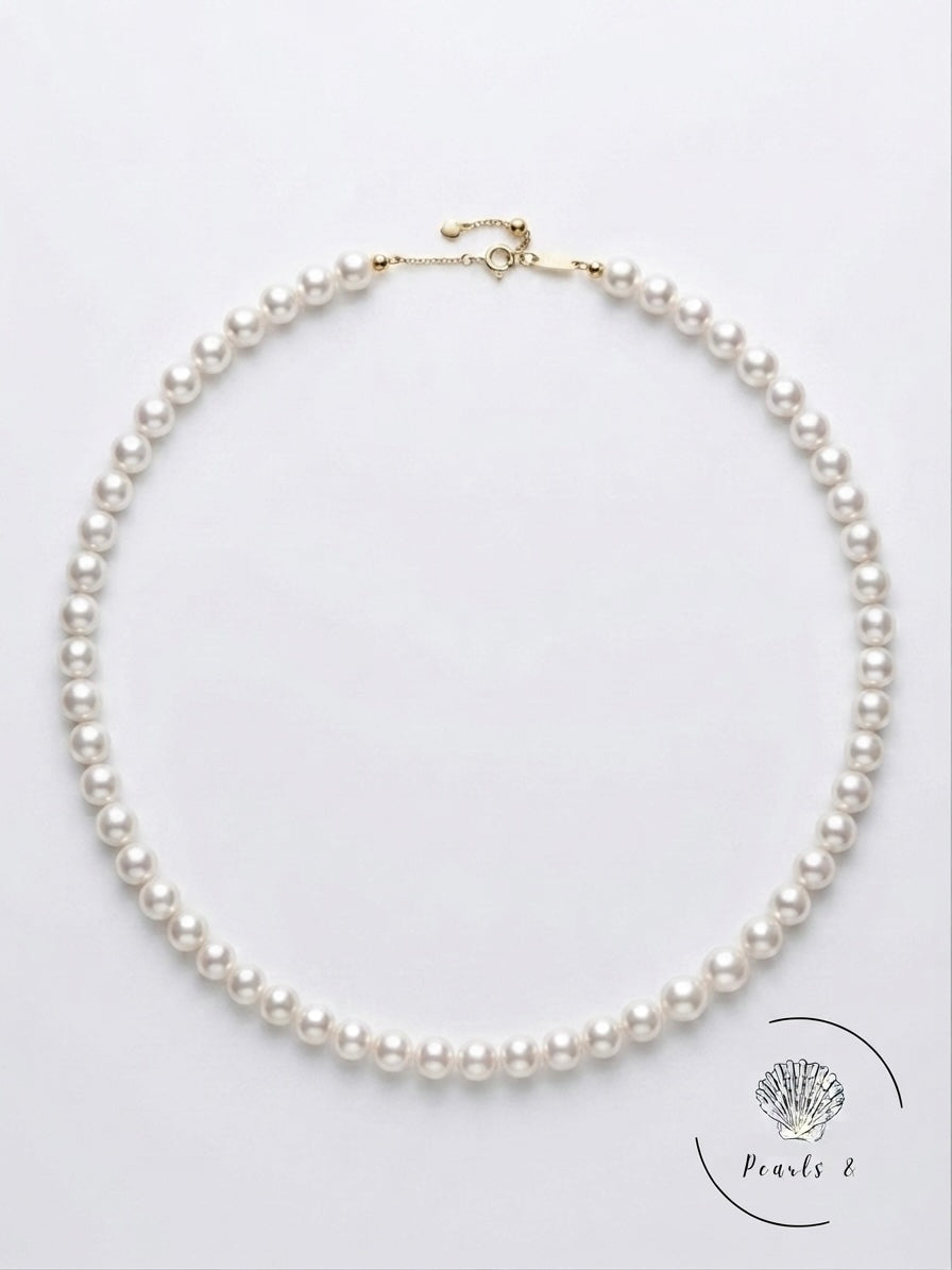 Classic white Akoya pearl necklace laid flat on a white background