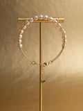 Freshwater pearl chain bracelet with heart charm on a gold display stand