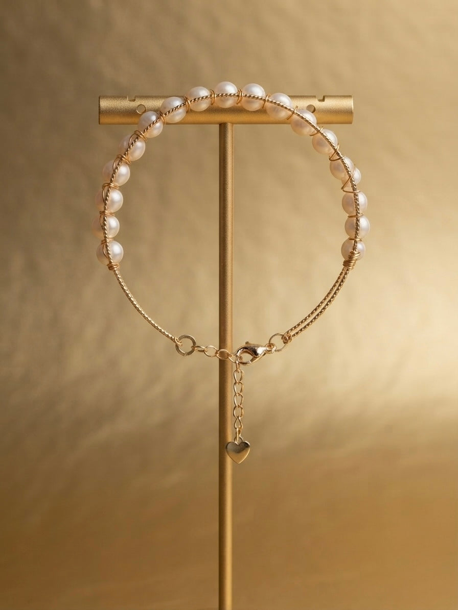 Freshwater pearl chain bracelet with heart charm on a gold display stand