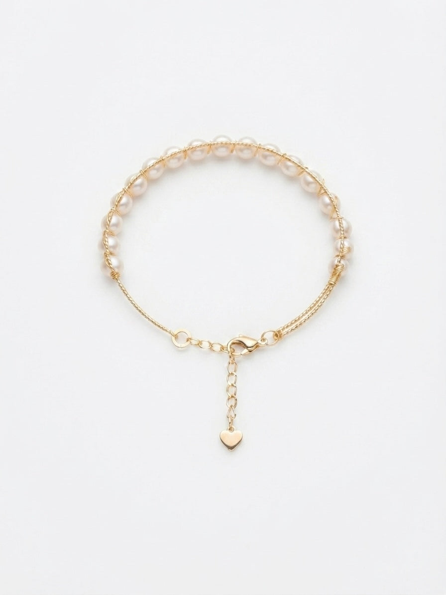 Freshwater pearl chain bracelet with heart charm on a white background