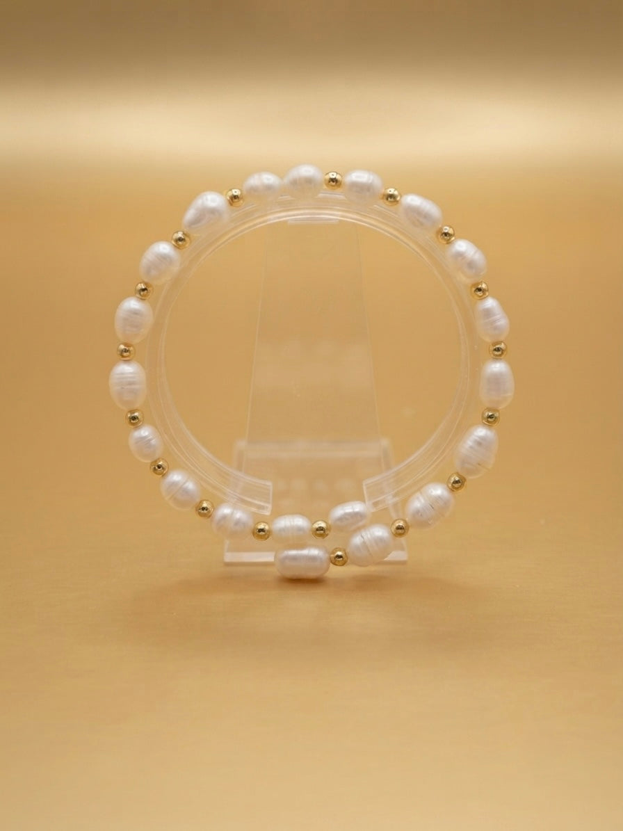 Freshwater pearl and gold bead stretch bracelet on a clear stand