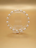 Freshwater pearl and gold bead stretch bracelet on a clear stand