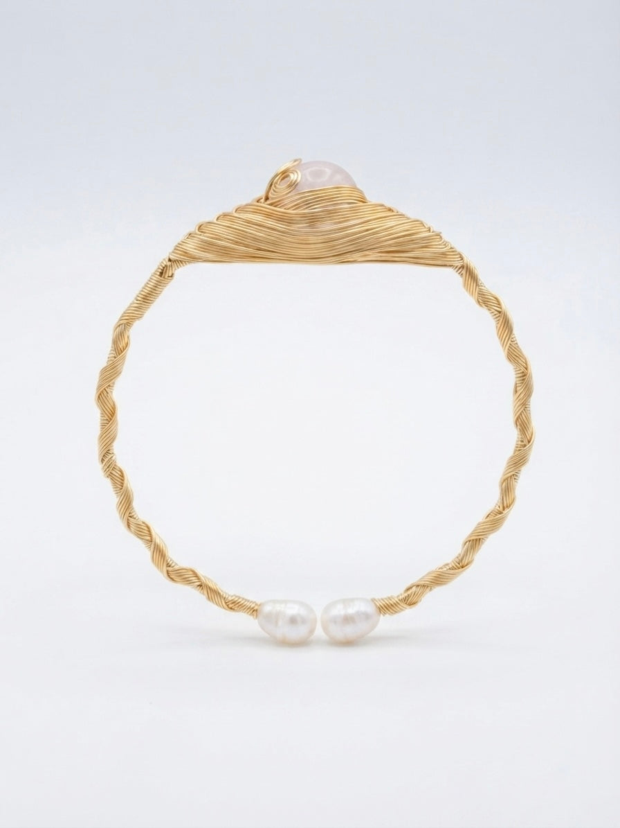 Twisted gold wire pearl cuff on a white background