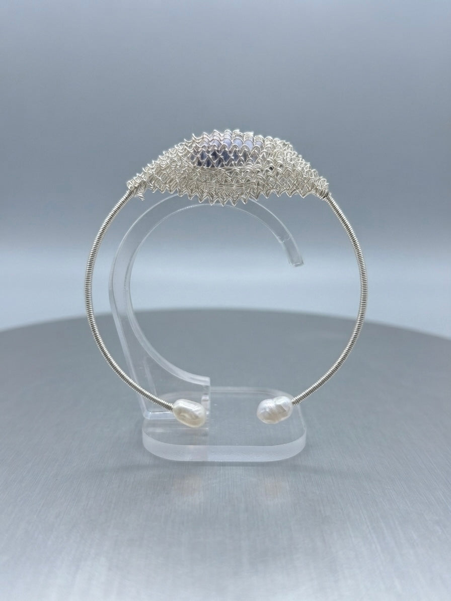 Silver sparkle freshwater pearl cuff on a clear display stand