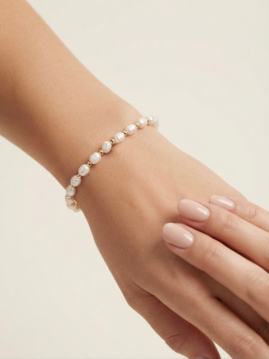 Freshwater pearl and gold bead stretch bracelet worn on the wrist
