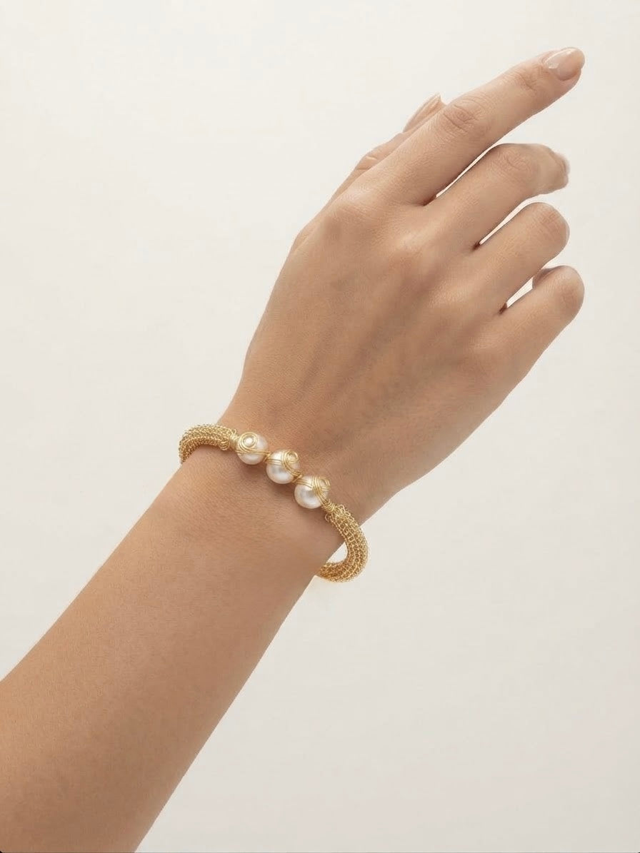 Woven gold triple pearl cuff worn on the wrist
