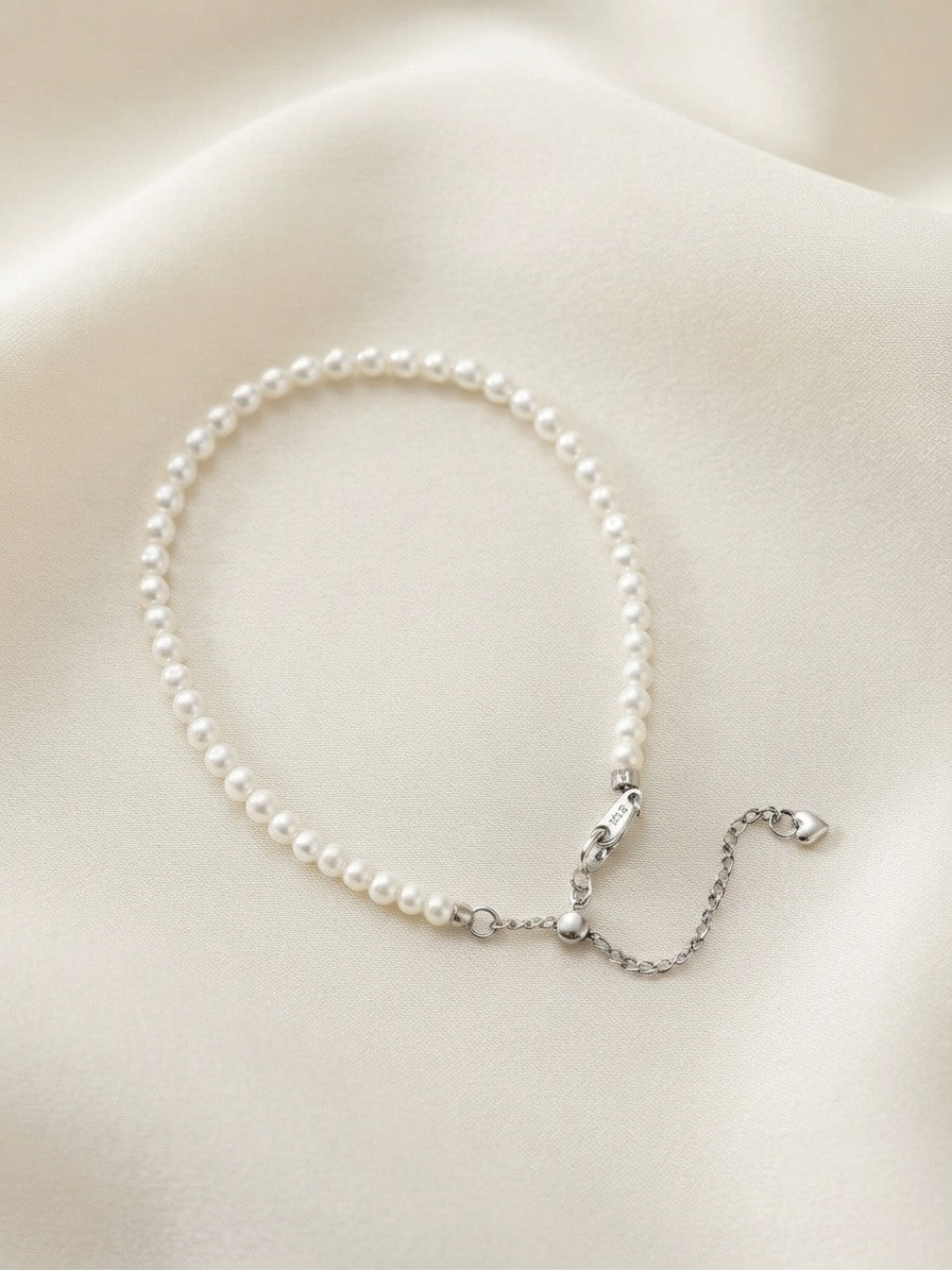Freshwater baby pearl bracelet with silver slider clasp on ivory silk