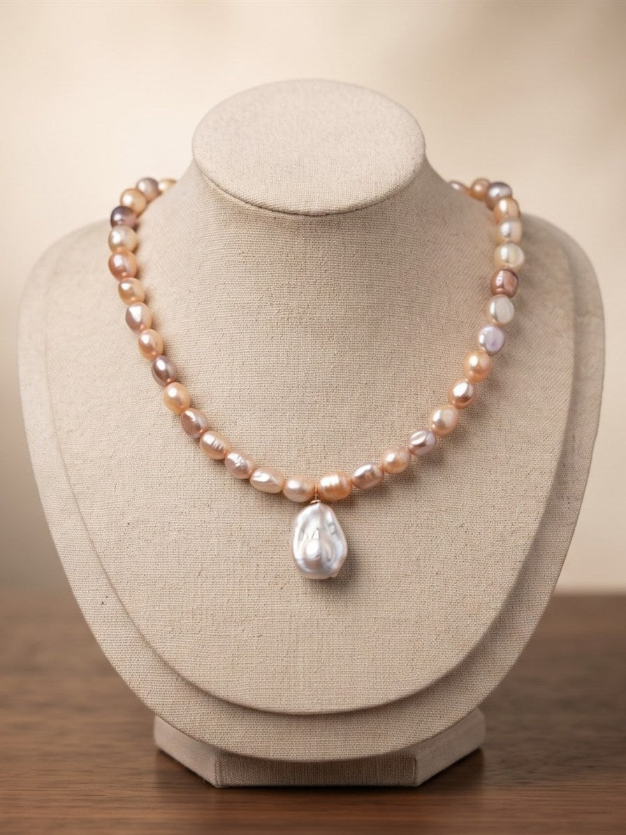 Pastel pearl necklace with baroque pearl drop on a linen display bust