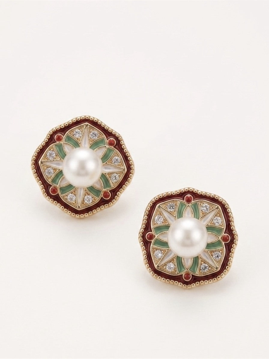 Freshwater pearl stud earrings with burgundy and green enamel star design, close-up