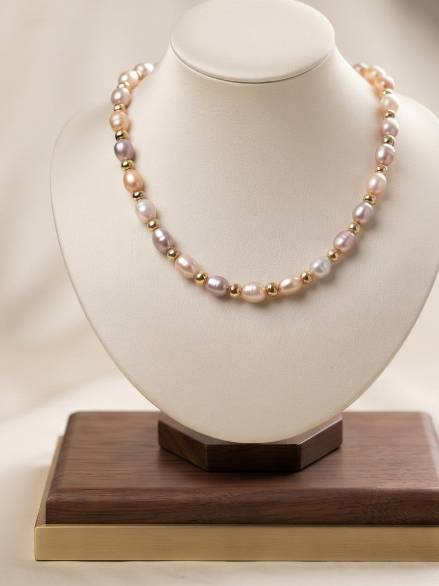 Pastel pearl and gold bead necklace on a cream display bust