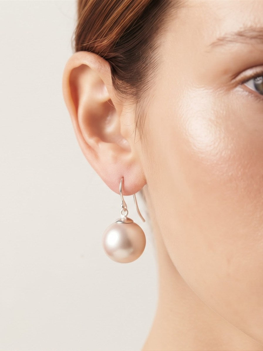 Large pearl drop earring worn on the ear, close-up