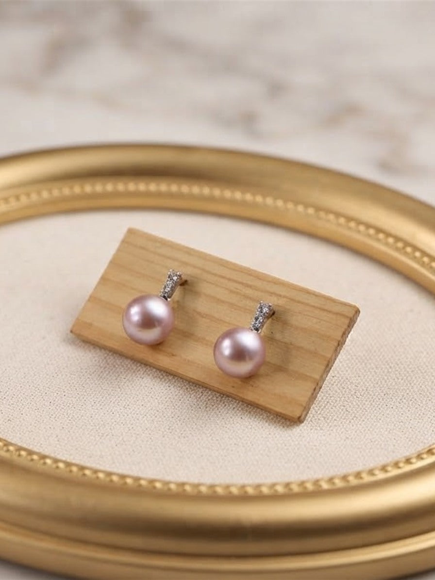 Lavender pearl drop earrings displayed on a gold oval frame