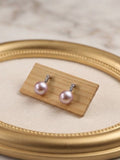 Lavender pearl drop earrings displayed on a gold oval frame