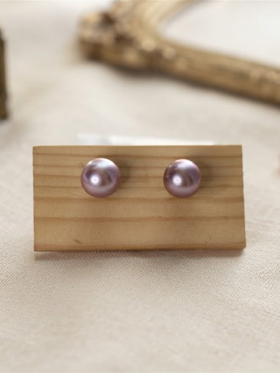 Classic lavender pearl stud earrings on a wooden display