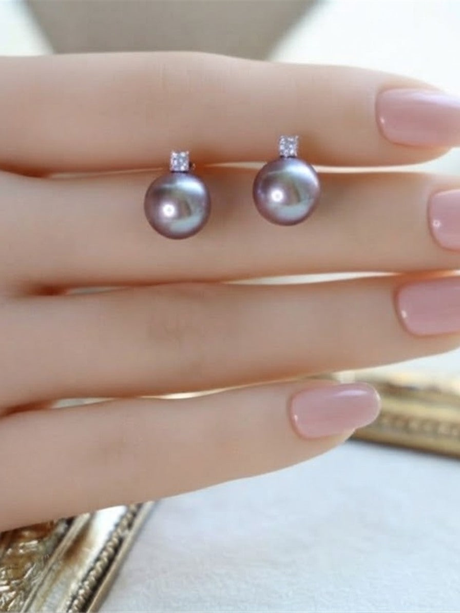 Lavender pearl solitaire stud earrings held between the fingers