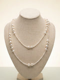 Long freshwater pearl necklace worn doubled on a linen display bust