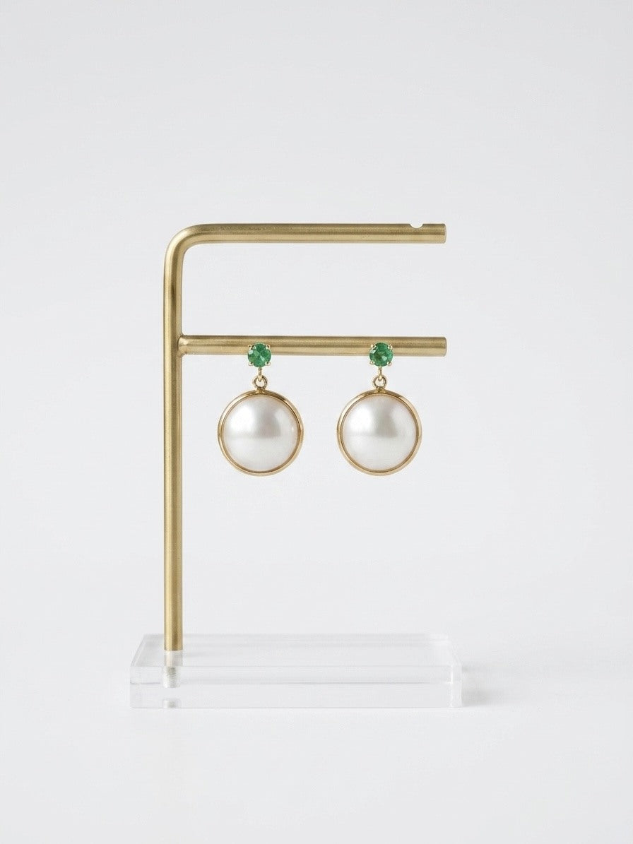 Mabe pearl and emerald earrings on a brass display stand