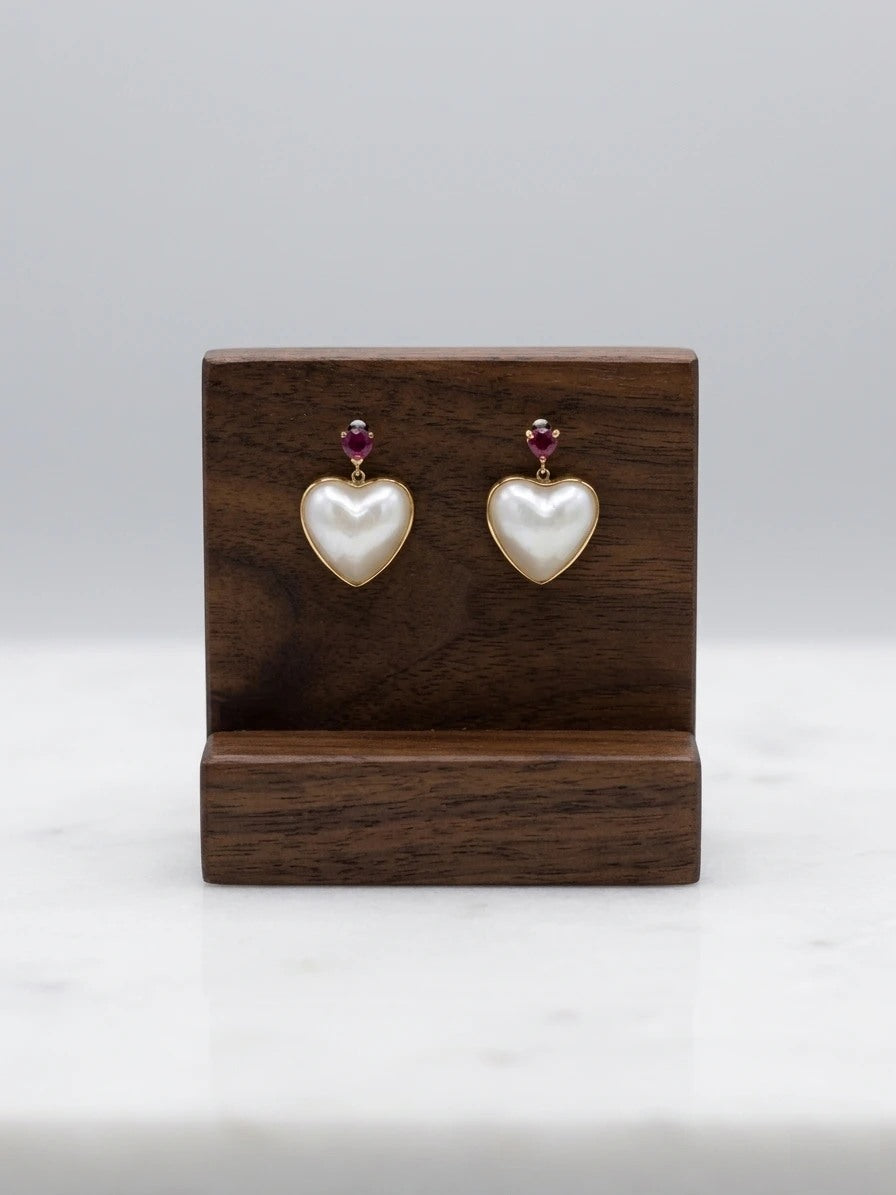Mabe pearl heart earrings with rubies on a walnut display stand