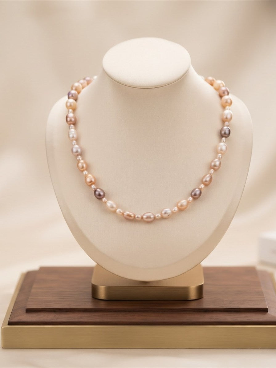 Pastel mixed pearl necklace on a cream display bust