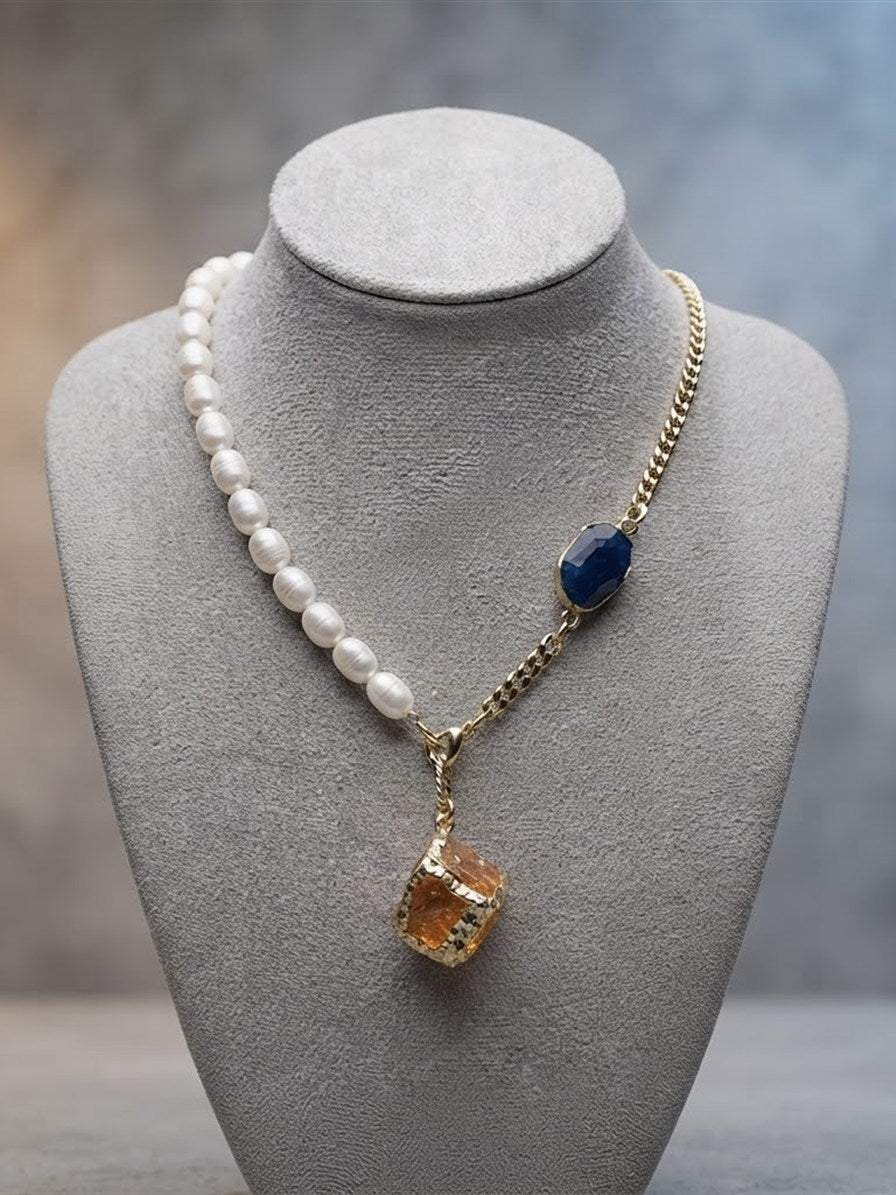 Freshwater pearl and gold chain necklace with navy and amber stones on a grey bust