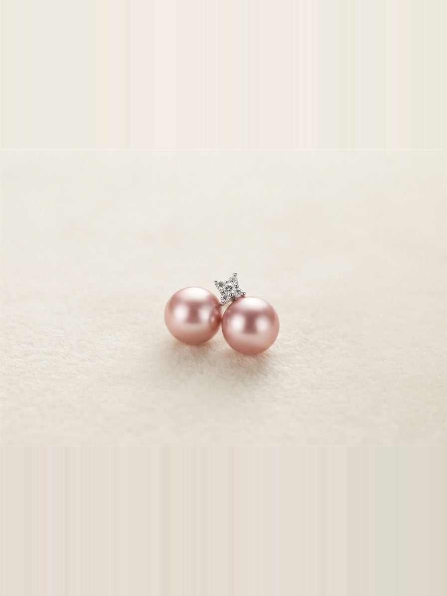 Pink pearl butterfly stud earrings on a cream background
