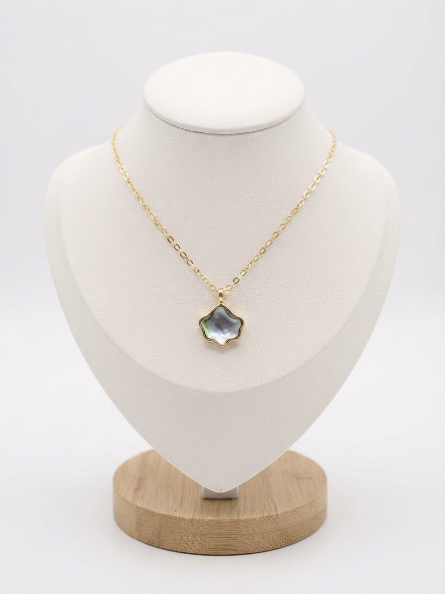 Iridescent wave pendant necklace in gold tone on a display bust