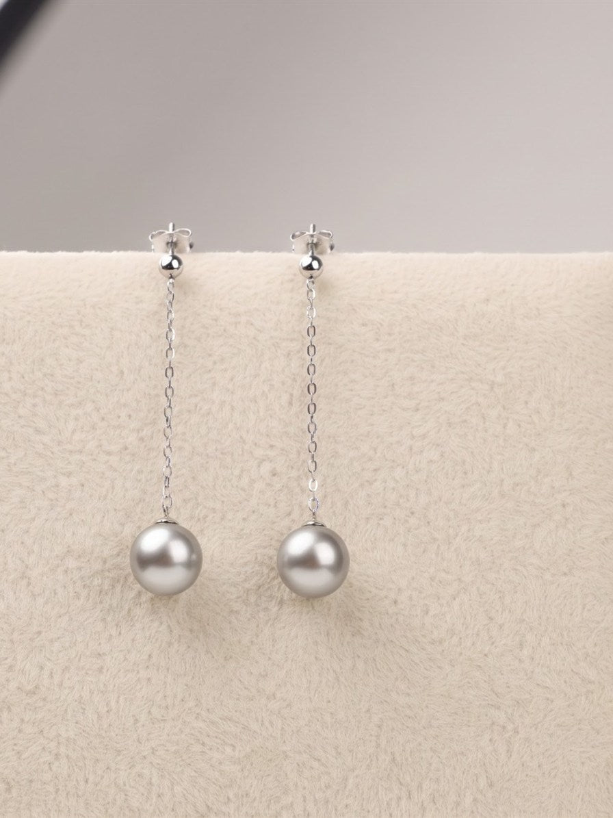 Tahitian pearl chain drop earrings on a cream velvet display