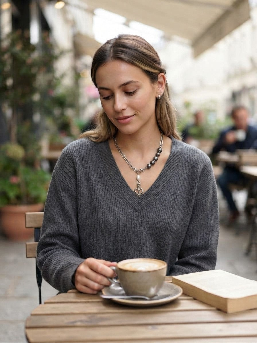 Tahitian pearl heart charm necklace worn with a grey jumper at a cafe