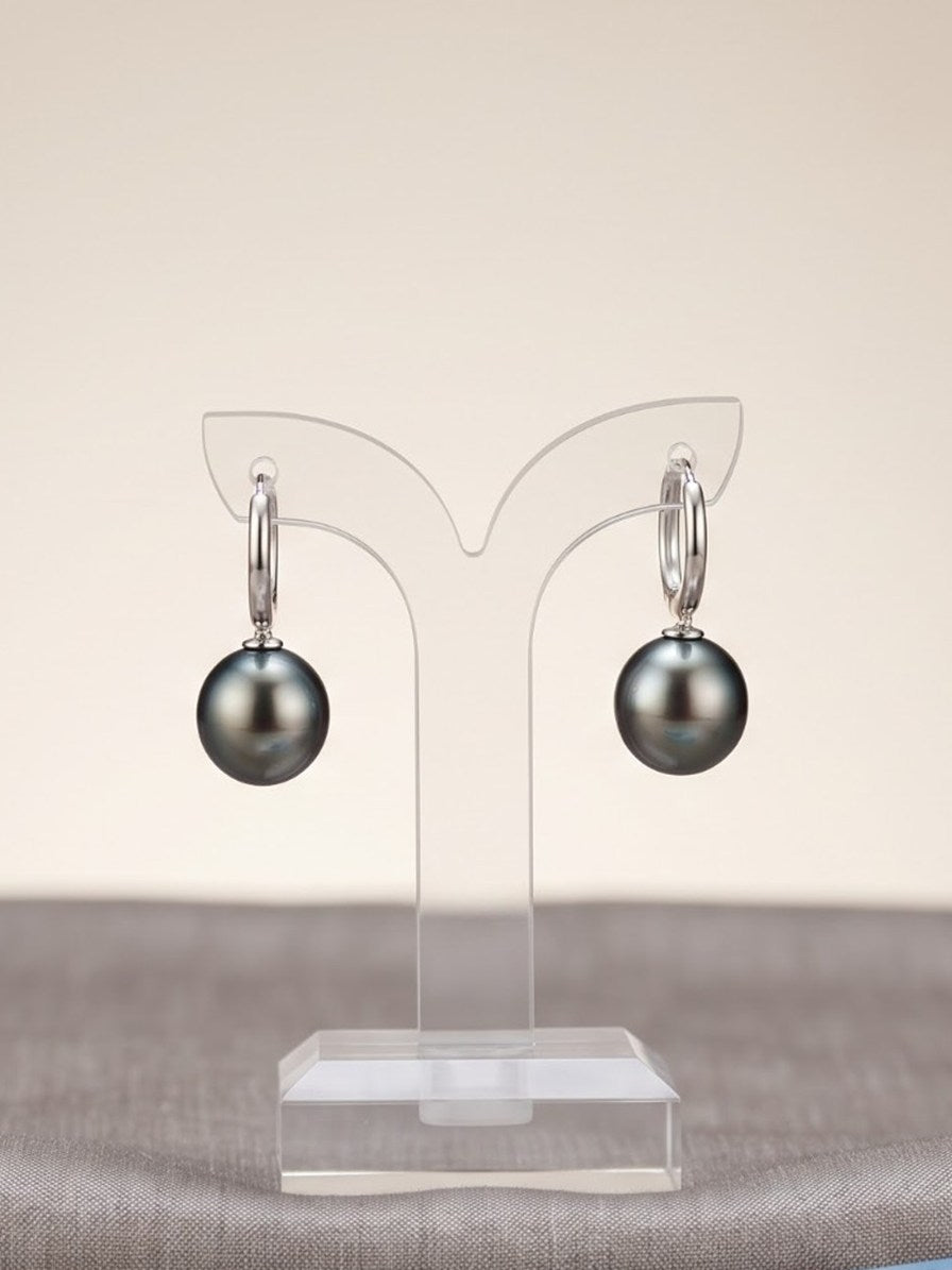 Tahitian pearl hoop earrings on a clear display stand
