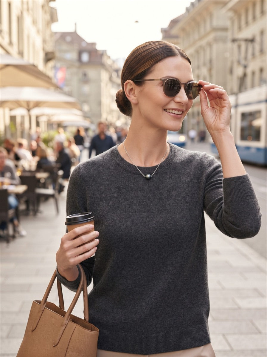 Woman wearing the Tahitian pearl solitaire necklace with a grey jumper in the city