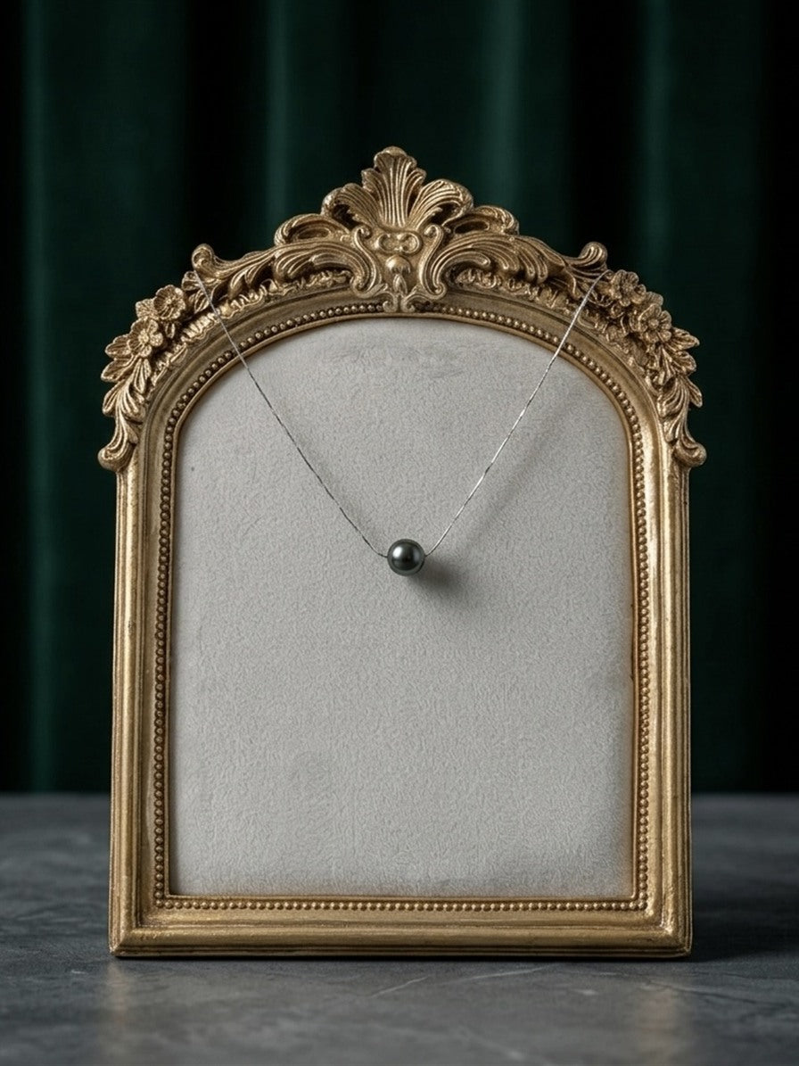 Tahitian pearl solitaire necklace displayed in a gold frame