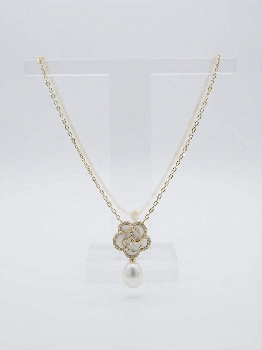 White flower pendant necklace with a freshwater pearl drop on a clear stand