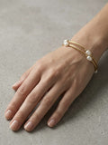 Twisted gold-tone wire wrap bracelet with white freshwater pearls worn on the wrist