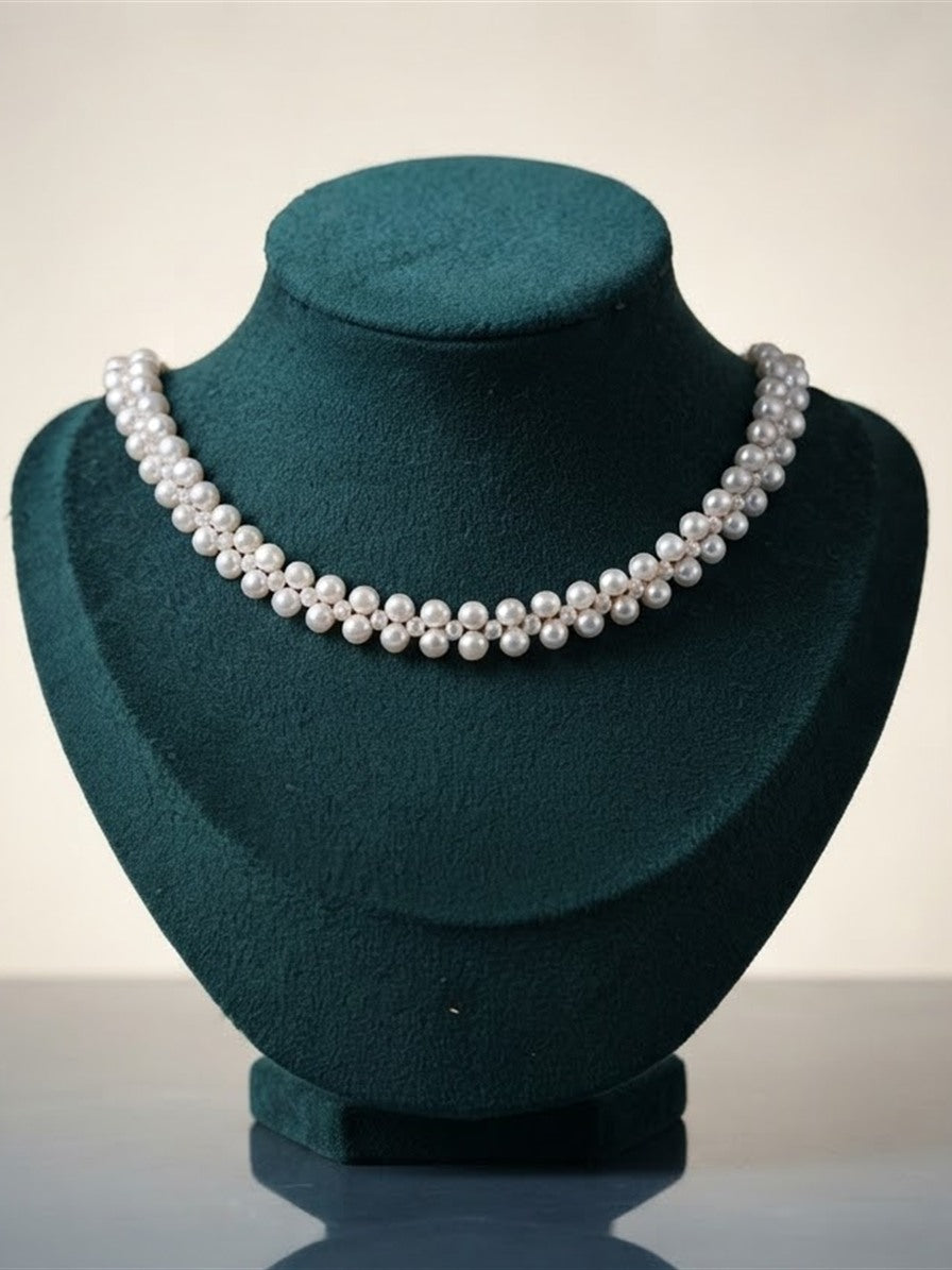 Woven freshwater pearl choker on a green velvet display bust
